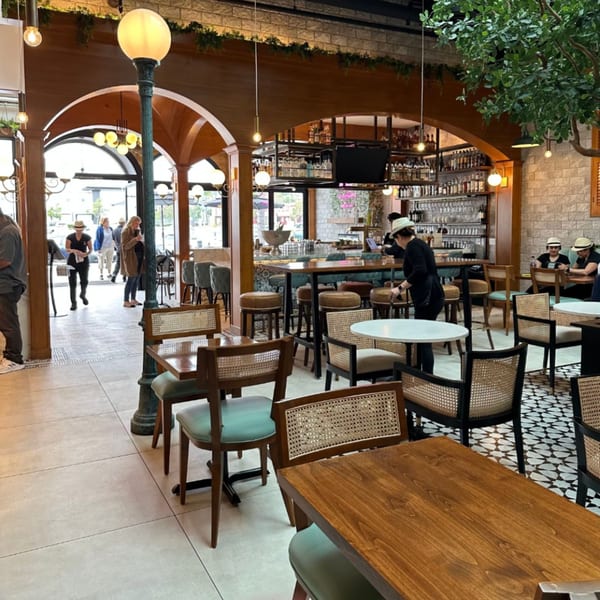 Havana Grill's interior, featuring wooden tables, cane chairs, a bar, and people dining.