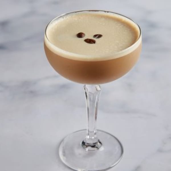 Espresso martini with three coffee beans on top of the foam, served in a coupe glass.