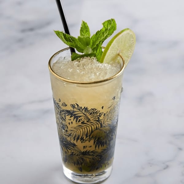 A refreshing mojito cocktail in a decorative glass, garnished with fresh mint and a lime slice.